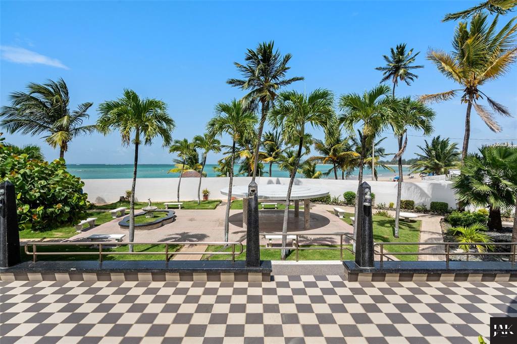 A tiled patio overlooks a landscaped courtyard with palm trees, a gazebo, and the ocean — 20 AMAPOLA STREET, CAROLINA, PR