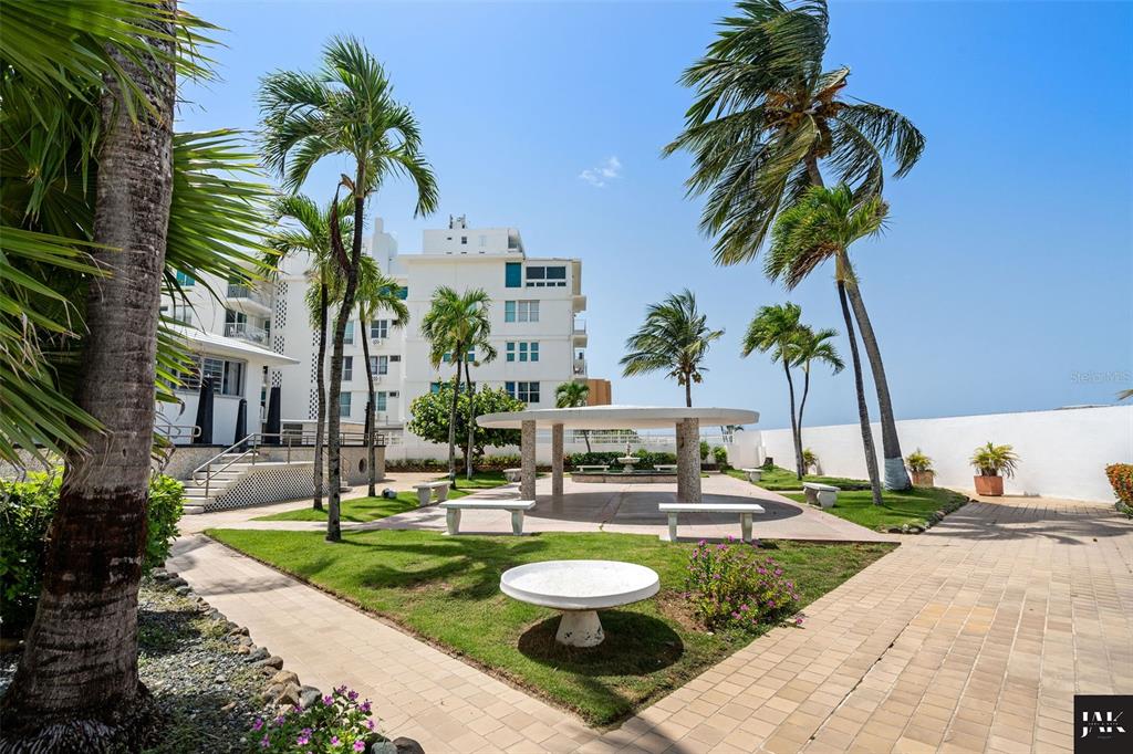A landscaped courtyard features palm trees, stone benches, a circular table, and a covered pavilion — 20 AMAPOLA STREET, CAROLINA, PR