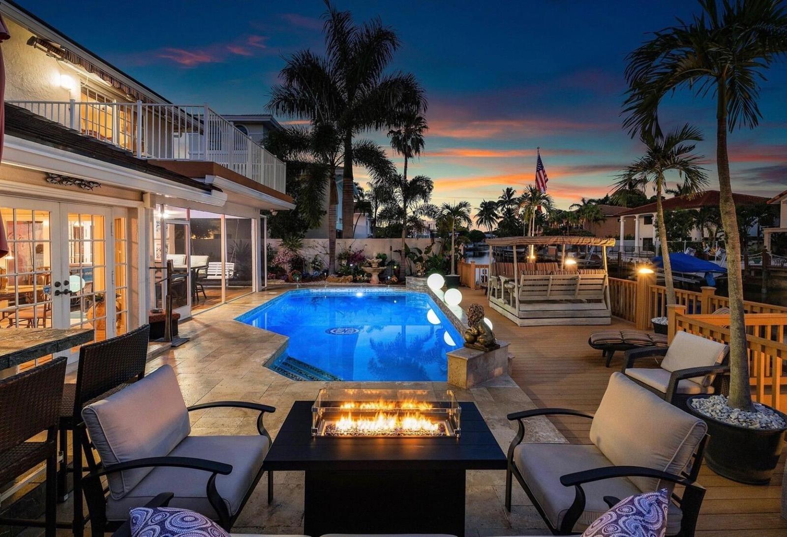 A backyard patio features a swimming pool, fire pit, seating area, and palm trees at sunset — 1548 SW 5th Avenue, Boca Raton FL 33432, BOCA RATON, FL