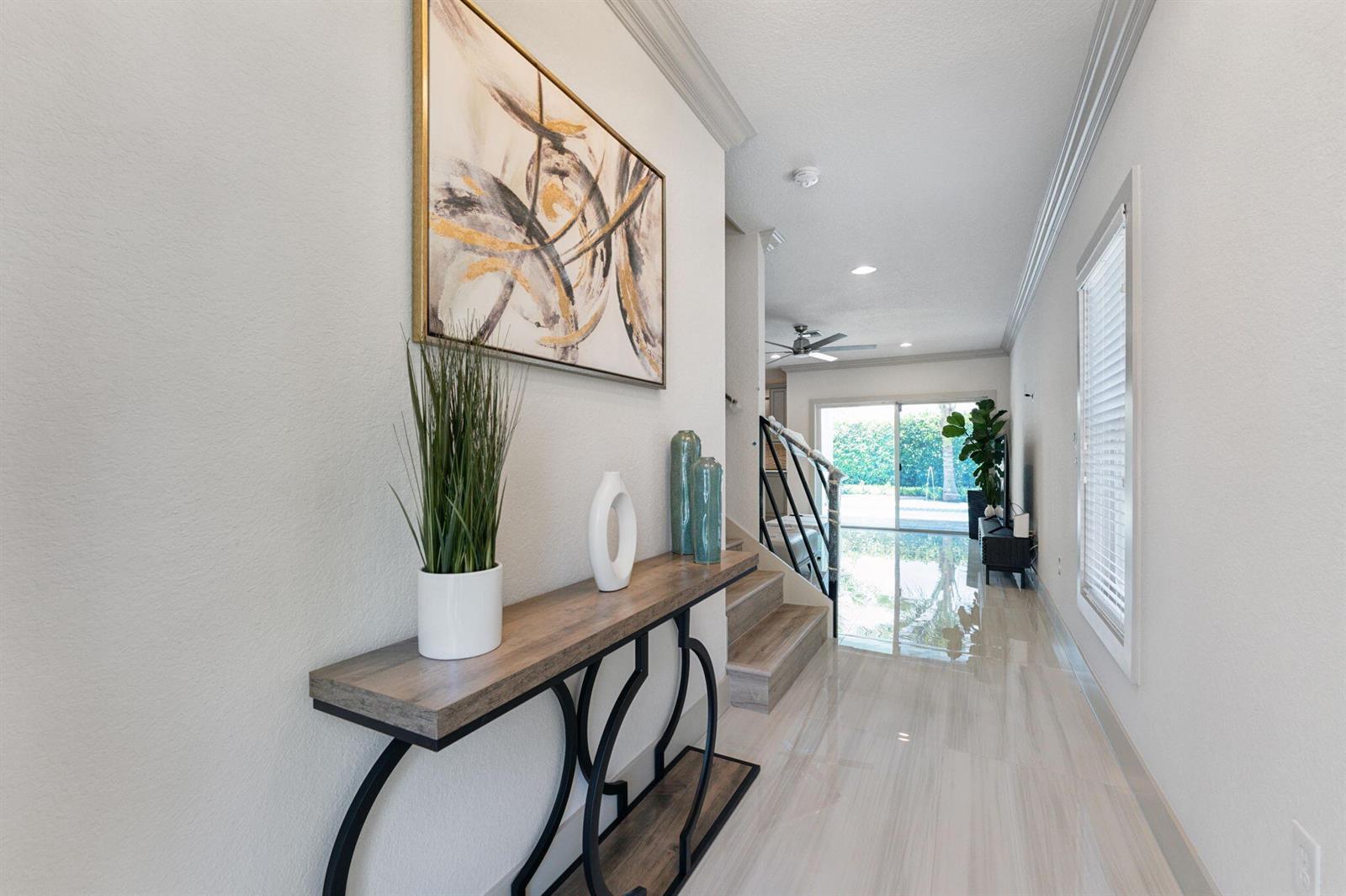 A hallway features a console table, abstract wall art, and stairs leading to a living area — 522 Lucky Lane, Delray Beach FL 33444, DELRAY BEACH, FL