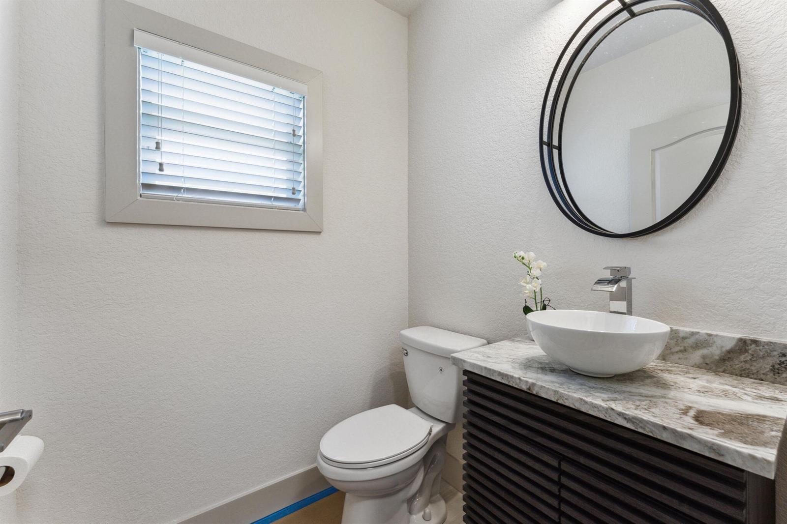 A powder room features a vessel sink on a marble vanity, a toilet, and a mirror — 522 Lucky Lane, Delray Beach FL 33444, DELRAY BEACH, FL