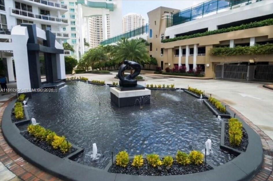 A dark sculpture sits in the center of a fountain surrounded by small yellow bushes — 901 Brickell Key Blvd # 2701, Miami FL 33131, MIAMI, FL