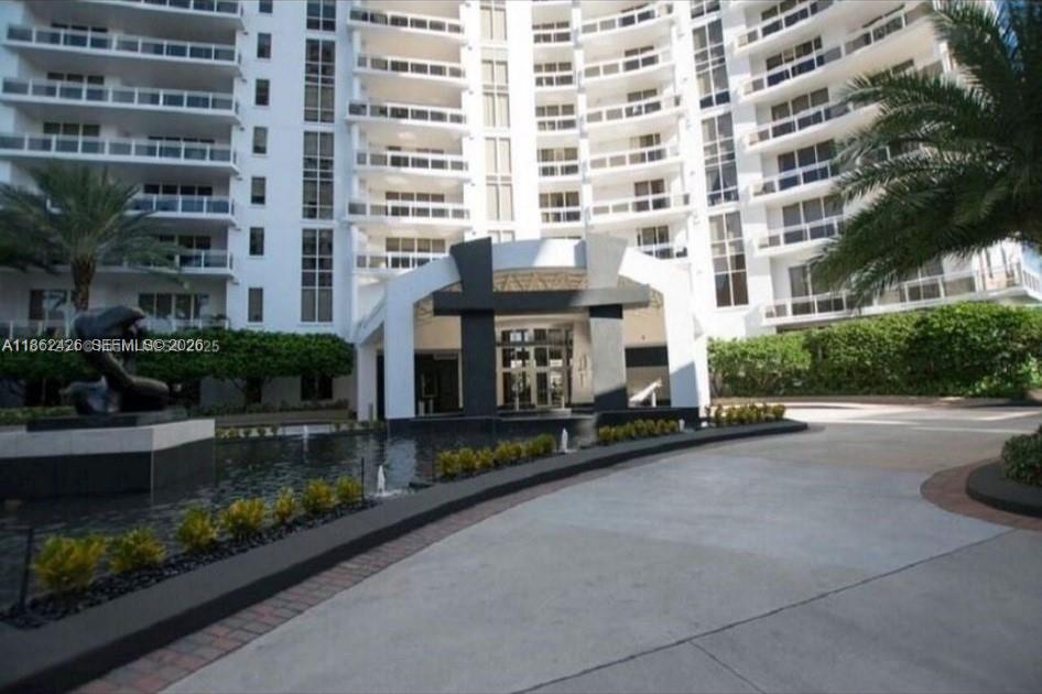 The exterior of a multi-story white apartment building features a fountain and a covered entrance — 901 Brickell Key Blvd # 2701, Miami FL 33131, MIAMI, FL