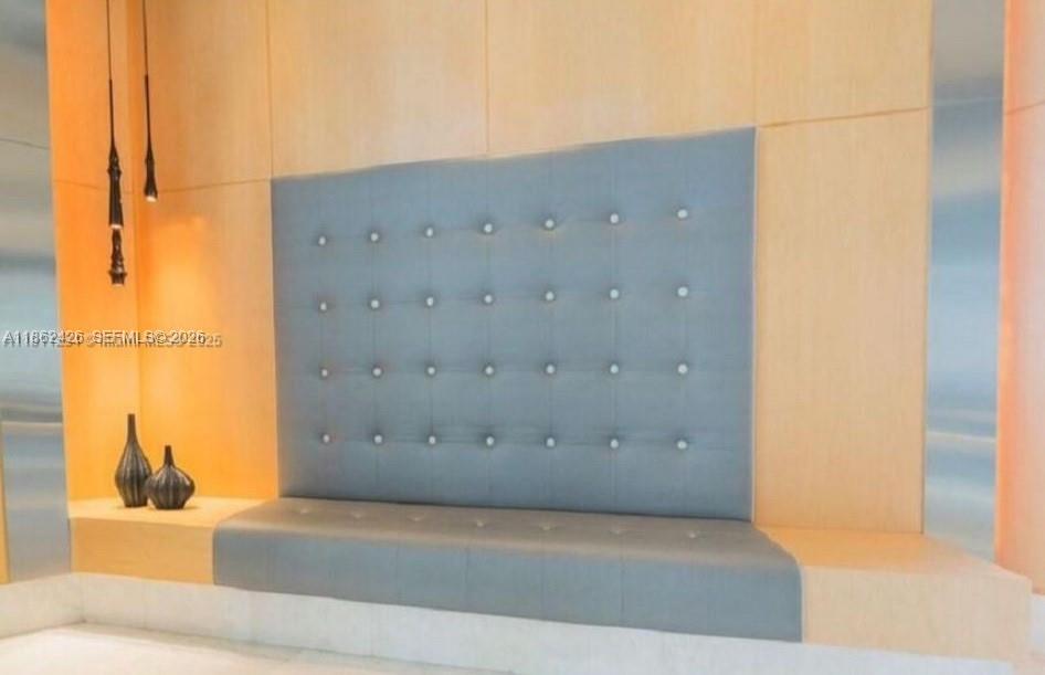 A tufted gray upholstered bench is set against a light wood paneled wall — 901 Brickell Key Blvd # 2701, Miami FL 33131, MIAMI, FL