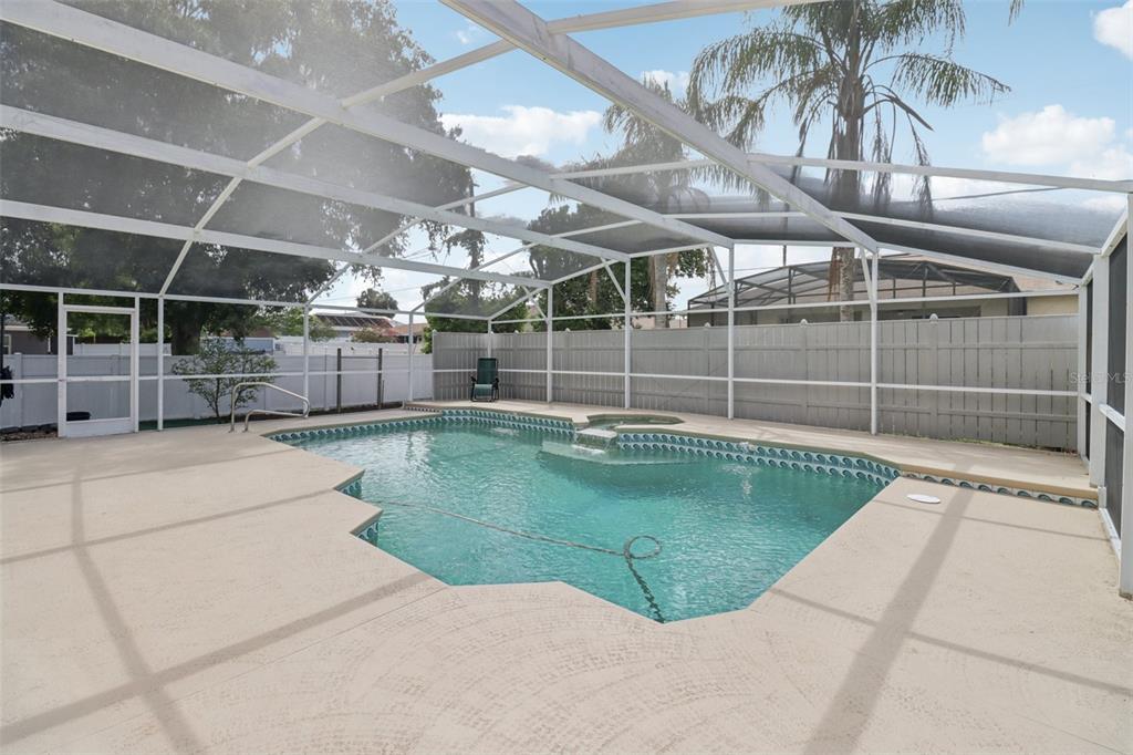 A screened-in swimming pool with a spa and concrete deck enclosed by a white fence — 1977 S OLD MILL DRIVE, DELTONA, FL