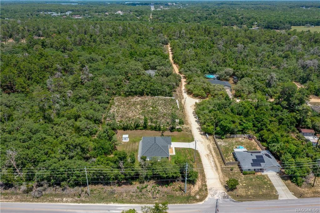 An aerial view shows a house on a wooded lot next to a dirt road — 3004 WOODHILL STREET, INVERNESS, FL