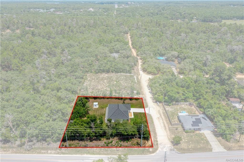An aerial view shows a single-family house on a wooded lot near a road — 3004 WOODHILL STREET, INVERNESS, FL
