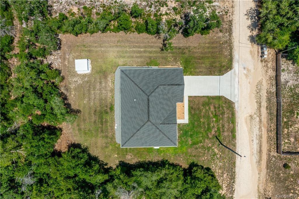 An aerial view shows a house with a dark roof, a concrete driveway, and a shed — 3004 WOODHILL STREET, INVERNESS, FL