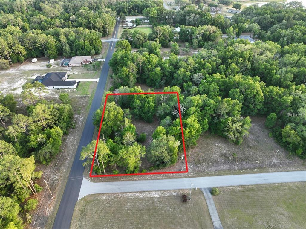 An aerial view shows a rectangular, wooded vacant lot outlined in red along a road — SW NORTH BEACH ROAD UNIT 104, DUNNELLON, FL