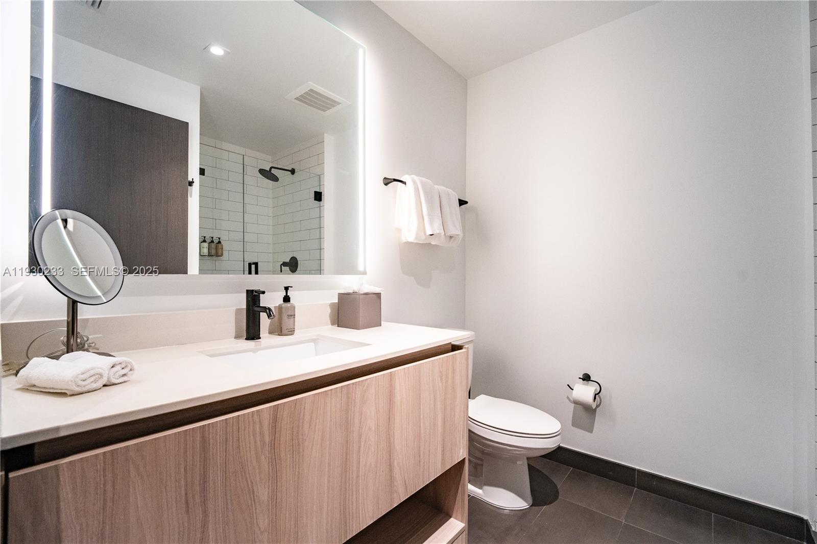 A modern bathroom features a floating wood vanity, a backlit mirror, and a walk-in shower — 398 NE 5th St # 2602, Miami FL 33132, MIAMI, FL