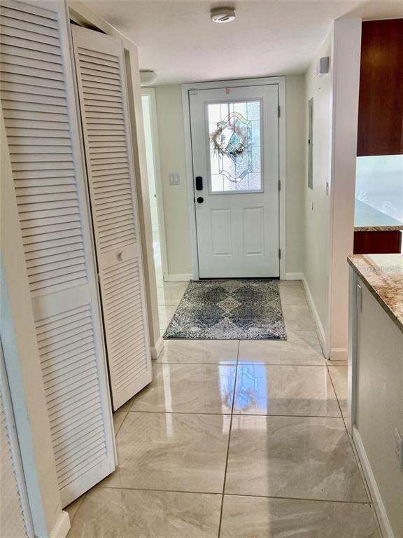 An entryway features light-colored tile flooring, a white front door, and louvered closet doors — 6430 SUN EAGLE LANE UNIT 203, BRADENTON, FL