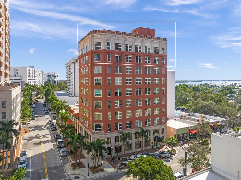 An exterior view of a tall, red-brick building with a white decorative cornice — 1330 MAIN STREET UNIT PH 9 & 10, SARASOTA, FL