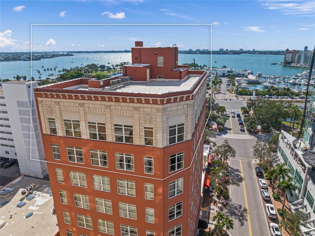 An aerial view of a multi-story orange building with a flat roof and water views — 1330 MAIN STREET UNIT PH 9 & 10, SARASOTA, FL