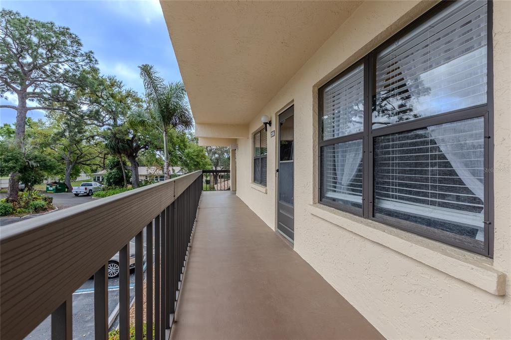 An outdoor balcony with a metal railing overlooks a parking area and trees — 305 30TH AVENUE W UNIT A208, BRADENTON, FL
