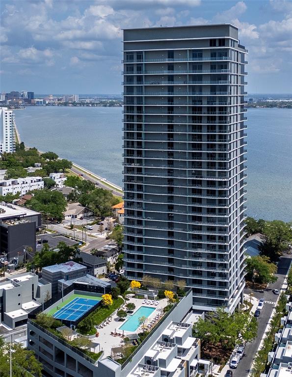 An aerial view shows a tall residential tower next to a pool and tennis court — 3015 S YSABELLA AVENUE UNIT 1202, TAMPA, FL