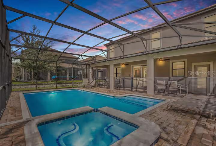 A screened-in patio features a swimming pool, a hot tub, and a paved deck area — 1454 BELLE TERRE ROAD, DAVENPORT, FL