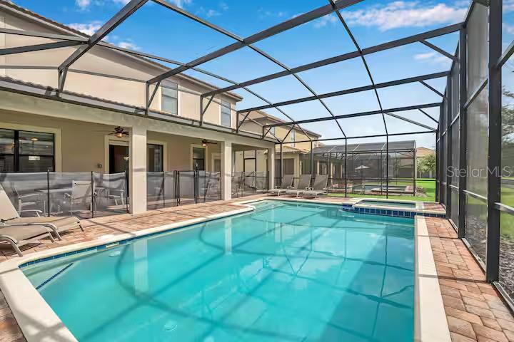 A swimming pool with a spa is enclosed by a screened lanai behind a house — 1454 BELLE TERRE ROAD, DAVENPORT, FL