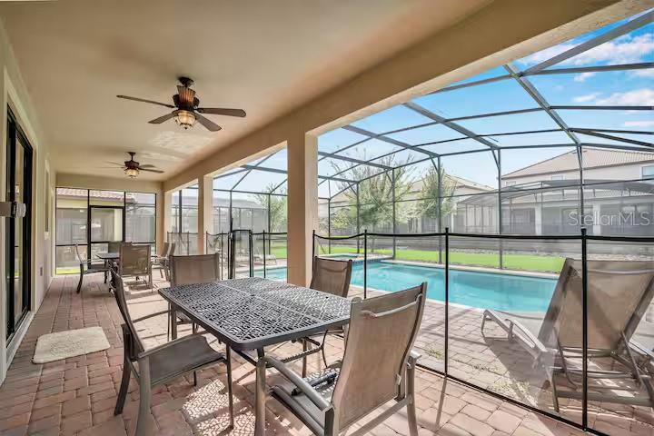 A covered patio with a dining set and pool safety fence overlooks a screened-in pool — 1454 BELLE TERRE ROAD, DAVENPORT, FL