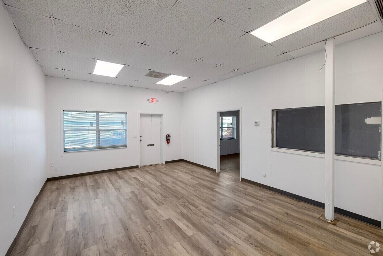 An empty office space features white walls, wood-look flooring, a drop ceiling, and an exit door — 400 NE 27th Street, Pompano Beach FL 33064, POMPANO BEACH, FL