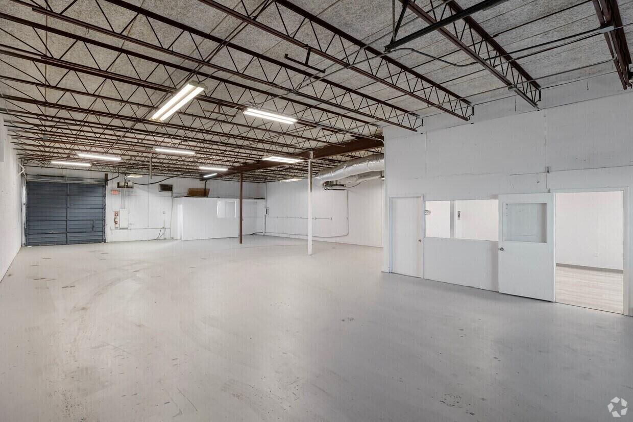 An open industrial warehouse space with a gray concrete floor and exposed metal ceiling trusses — 400 NE 27th Street, Pompano Beach FL 33064, POMPANO BEACH, FL