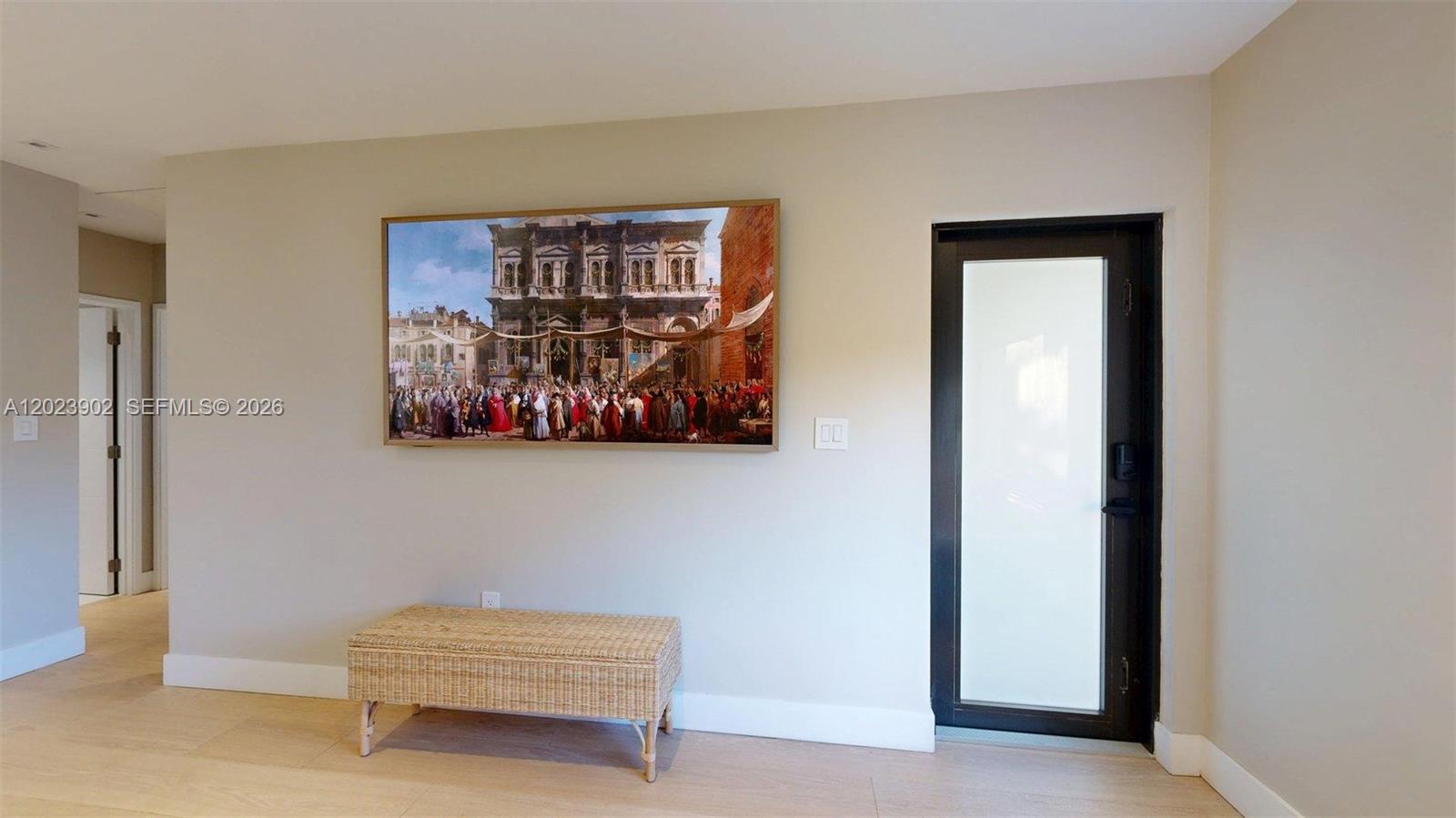 A room with light wood floors, a wicker bench, a wall-mounted television, and a glass door — 1277 SW 19th St, Miami FL 33145, MIAMI, FL