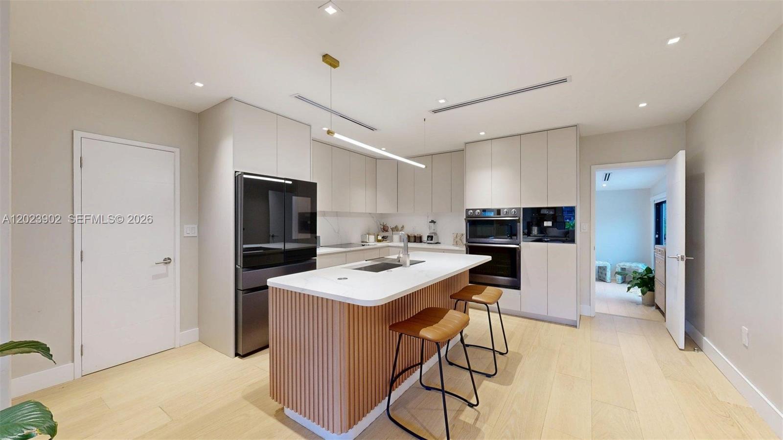 A modern kitchen features a slatted wood island, white cabinetry, and light wood flooring — 1277 SW 19th St, Miami FL 33145, MIAMI, FL