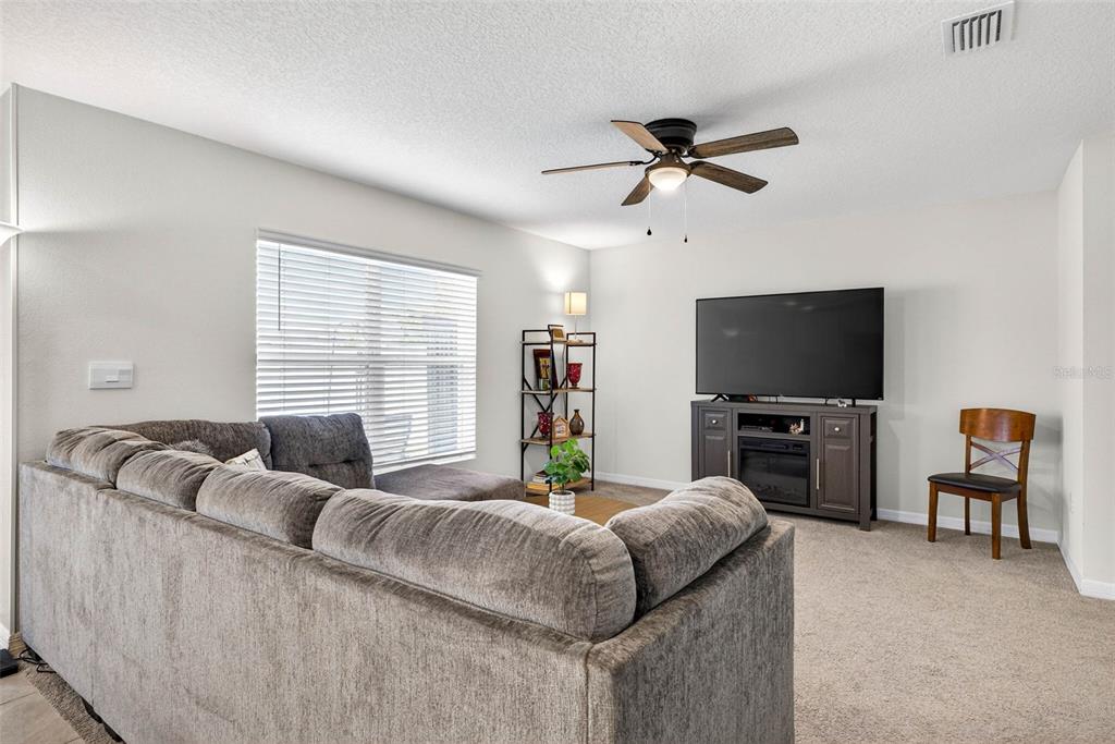A kitchen features white cabinets, granite countertops, a center island with bar stools, and dining — 13765 WHISKEY DAISY DRIVE, DADE CITY, FL