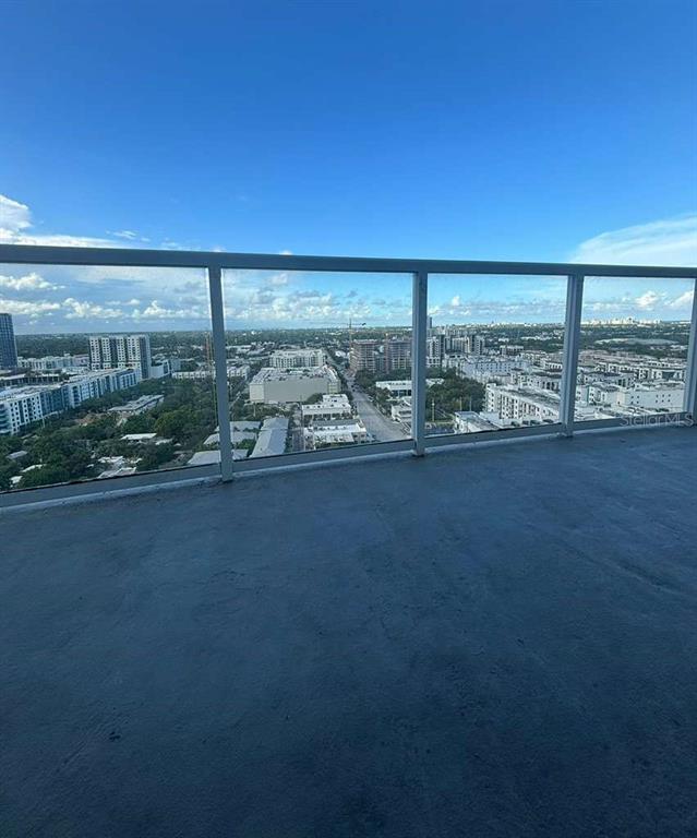 A high-rise balcony with a glass railing overlooks a sprawling urban landscape under a blue sky — 315 NE 3RD AVENUE UNIT 2009, FORT LAUDERDALE, FL