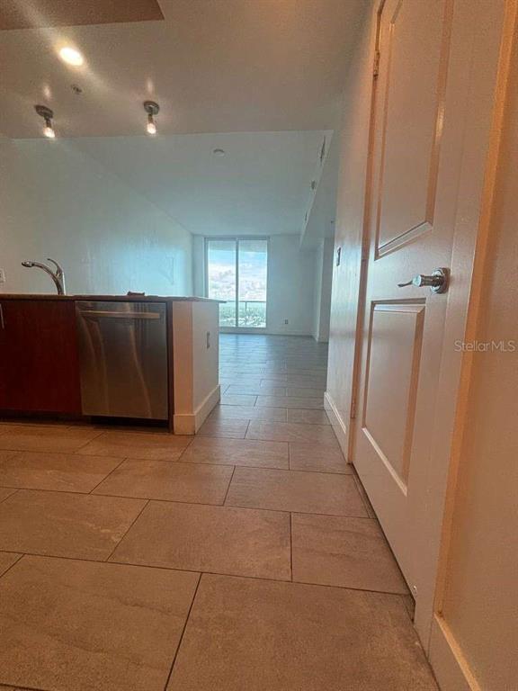 A kitchen with a stainless steel dishwasher and tile flooring leads to a living area — 315 NE 3RD AVENUE UNIT 2009, FORT LAUDERDALE, FL