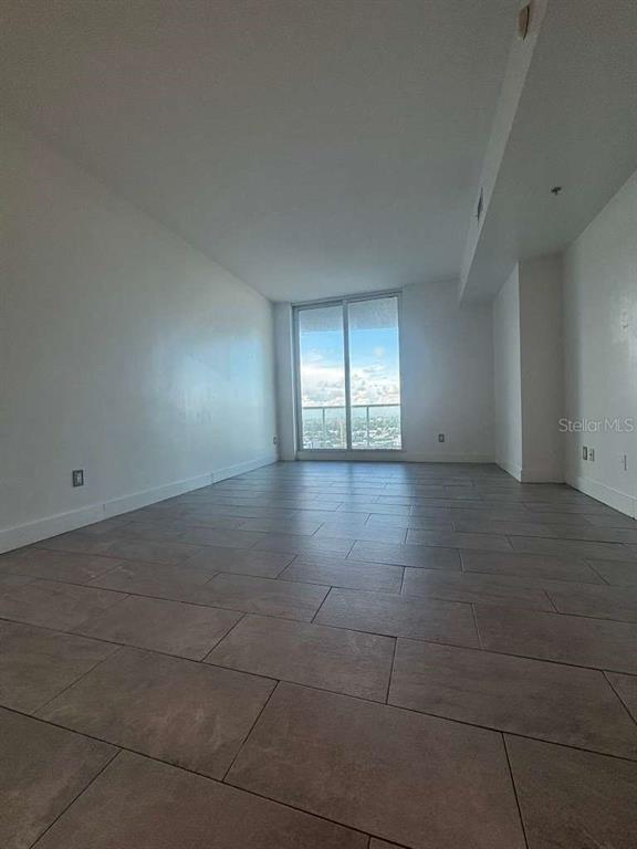 An empty room with light-colored walls, large windows, and gray tile flooring — 315 NE 3RD AVENUE UNIT 2009, FORT LAUDERDALE, FL