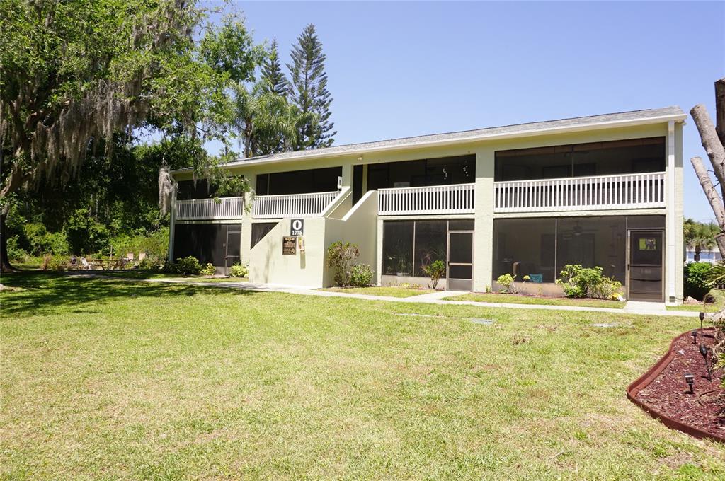A two-story apartment building with screened-in balconies and a grassy lawn in front — 1775 CUPECOY CIRCLE UNIT O6, LUTZ, FL
