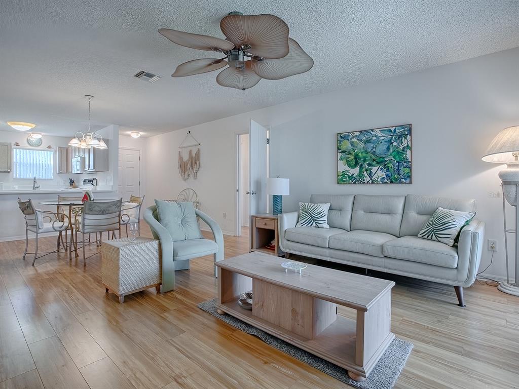 A living room with light wood floors, a sofa, an armchair, and a ceiling fan — 3337 ASHBROOK PLACE, THE VILLAGES, FL