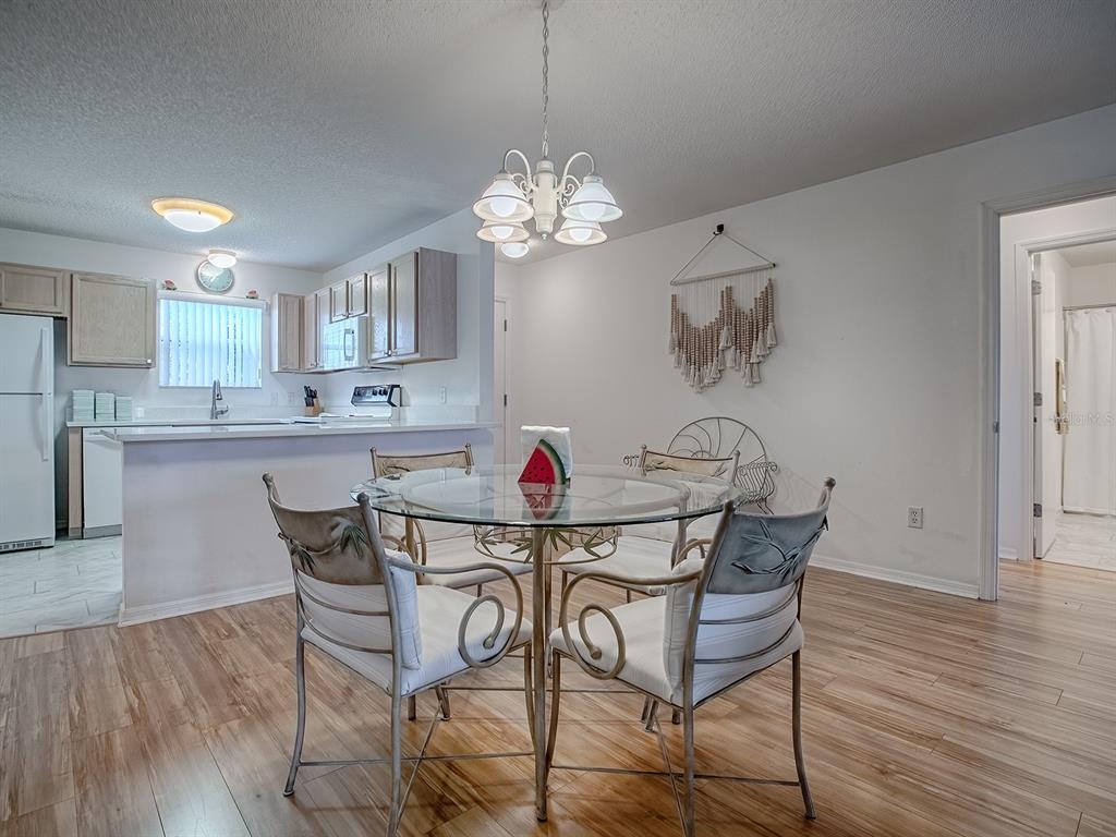 A dining area with a glass table and chairs sits adjacent to a kitchen — 3337 ASHBROOK PLACE, THE VILLAGES, FL