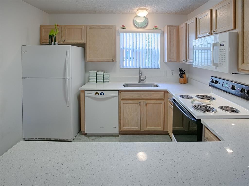 A kitchen features light wood cabinets, white appliances, and a white speckled countertop — 3337 ASHBROOK PLACE, THE VILLAGES, FL