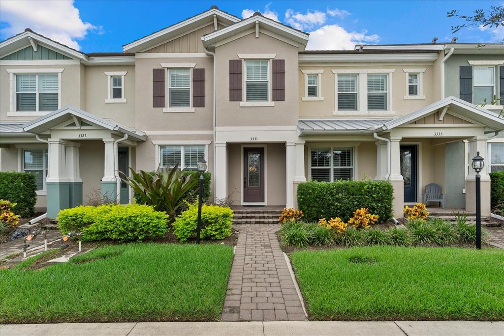 A row of three attached townhouses features beige stucco siding, dark shutters, and covered front porches — 3331 CHESTERTOWN LOOP, BRADENTON, FL
