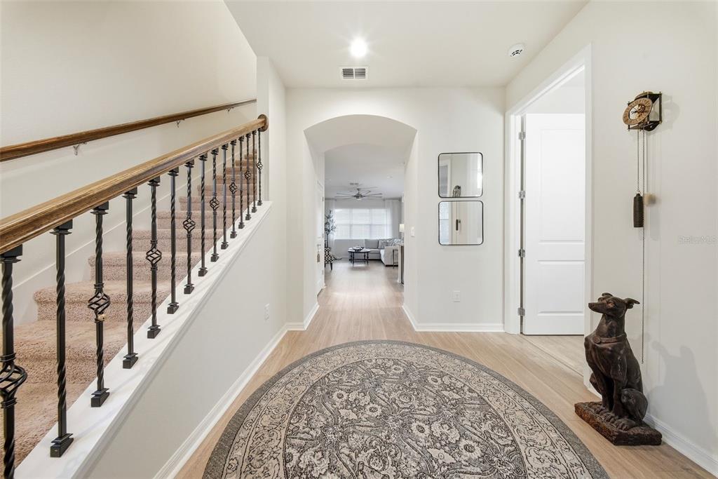 A carpeted staircase with iron railings leads to a hallway with a round area rug — 5920 VILLAGE CENTER DRIVE, LITHIA, FL