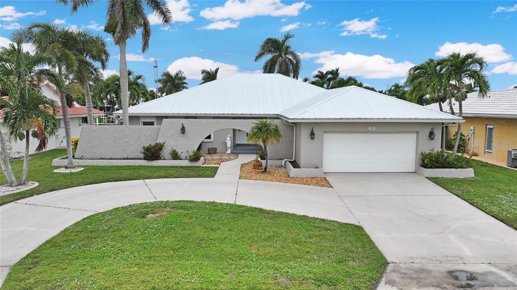 A single-story house with a white metal roof, stucco exterior, and a two-car garage — 931 BAL HARBOR BOULEVARD, PUNTA GORDA, FL