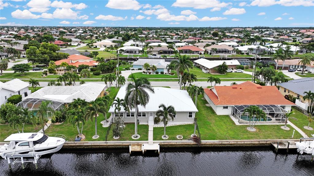 An aerial view shows three waterfront houses with pools and boat docks along a canal — 931 BAL HARBOR BOULEVARD, PUNTA GORDA, FL