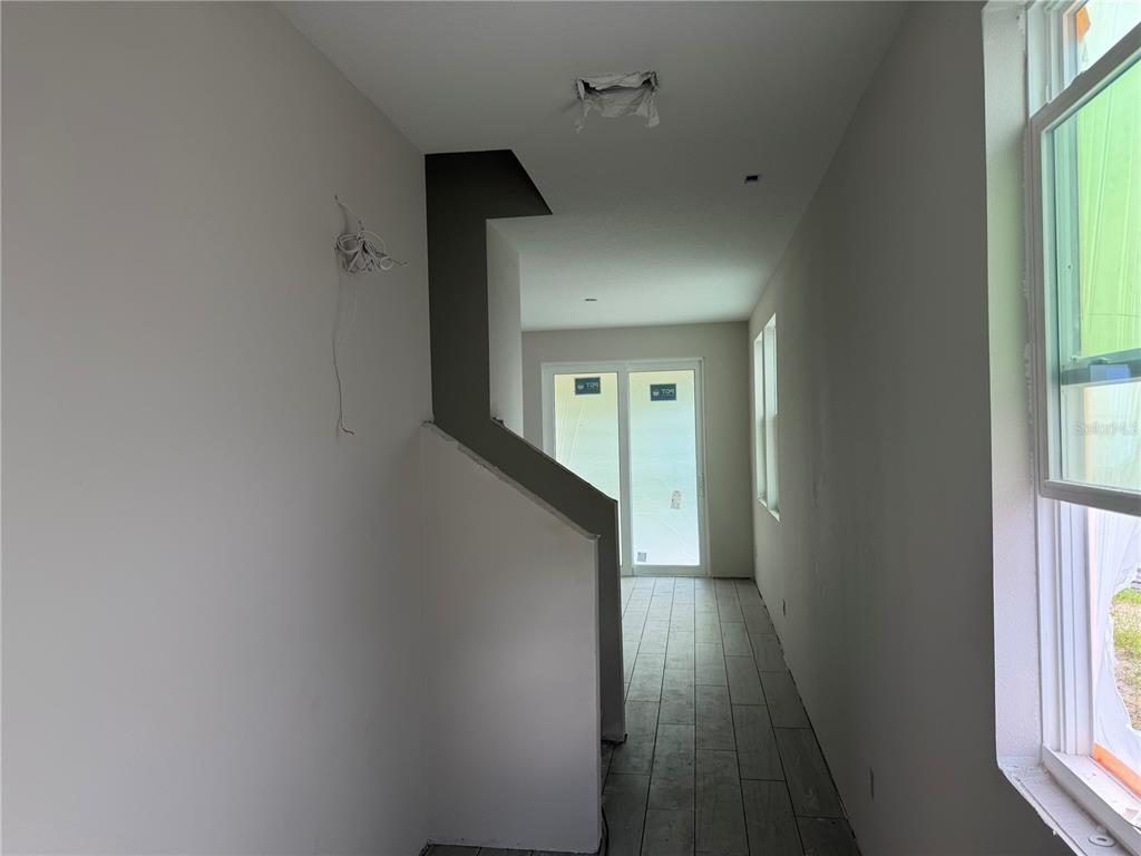 An interior view shows a hallway with tile flooring leading toward a glass sliding door — 7542 DEER VALLEY CIRCLE, TAMPA, FL