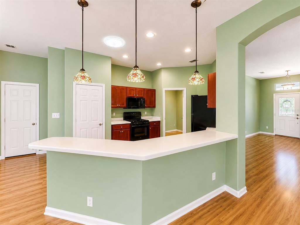 A kitchen with a breakfast bar, green walls, wooden cabinets, and hardwood flooring — 4908 CYPRESS HEAD COURT, LEESBURG, FL