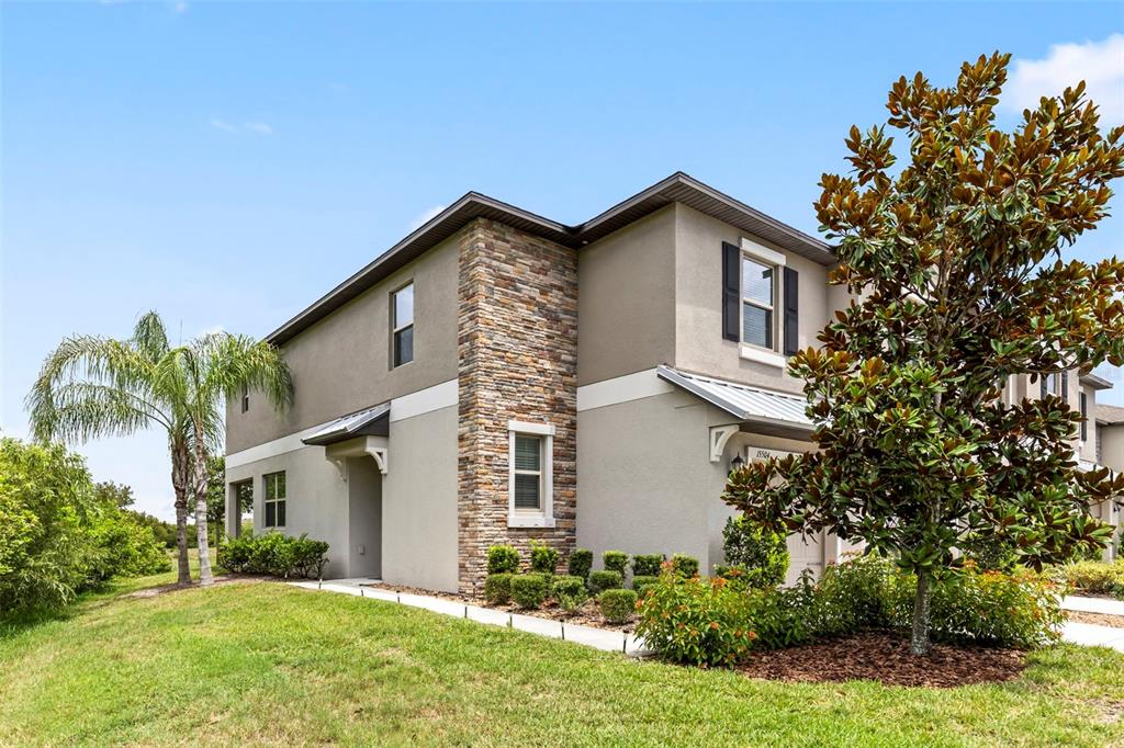 A two-story house with a stone-accented facade, a palm tree, and a large magnolia tree — 15504 FLORENCE HOLLOW PLACE, RUSKIN, FL