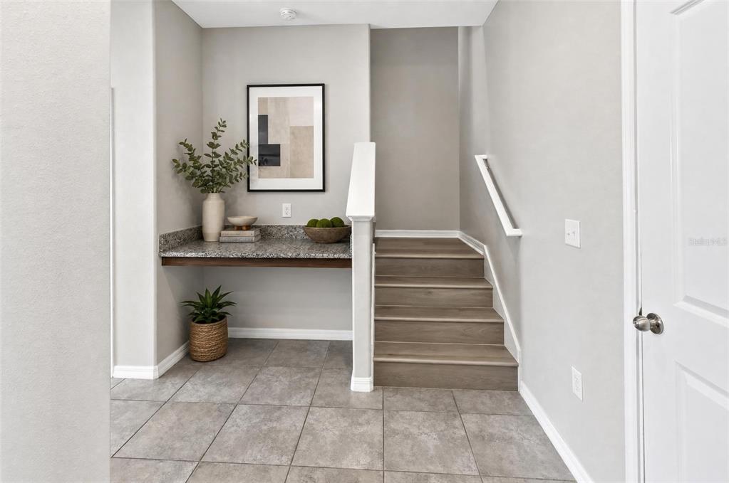 An entryway features a granite-topped built-in desk, stairs with wood-look treads, and tile flooring — 15504 FLORENCE HOLLOW PLACE, RUSKIN, FL