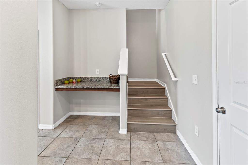 A built-in granite desk sits next to a staircase with wood-look steps and tile flooring — 15504 FLORENCE HOLLOW PLACE, RUSKIN, FL