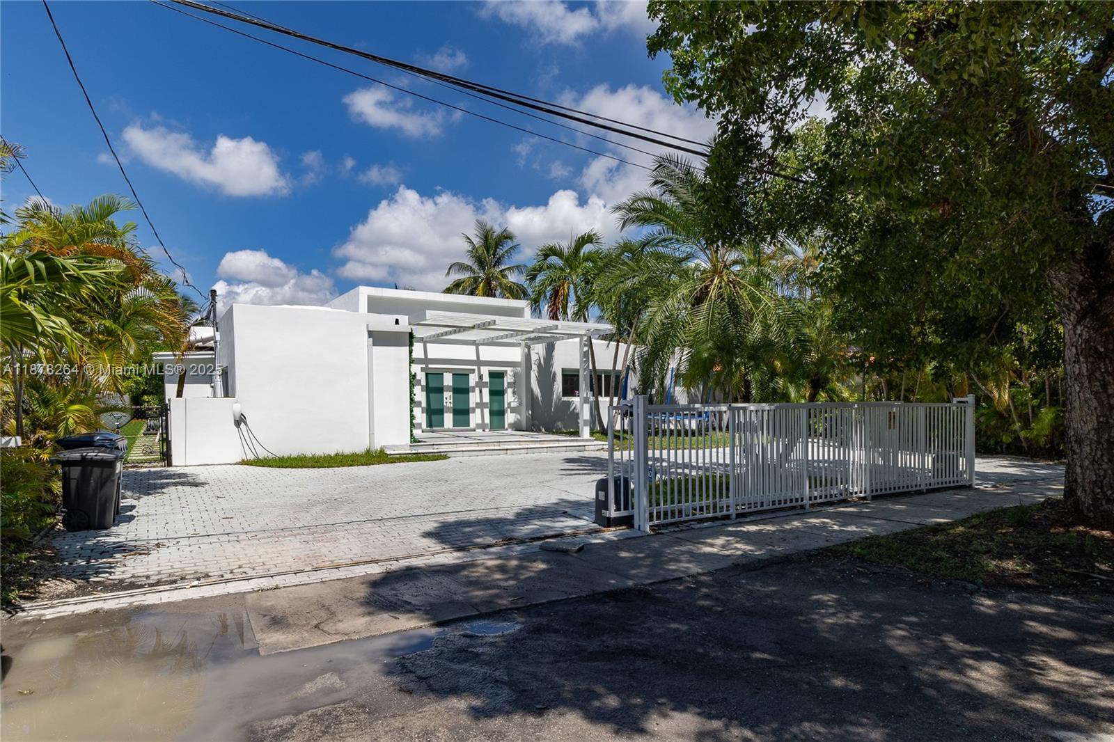 A white modern house with a flat roof and a paved driveway behind a fence — 1215 N Biscayne Point Rd, Miami Beach FL 33141, MIAMI BEACH, FL