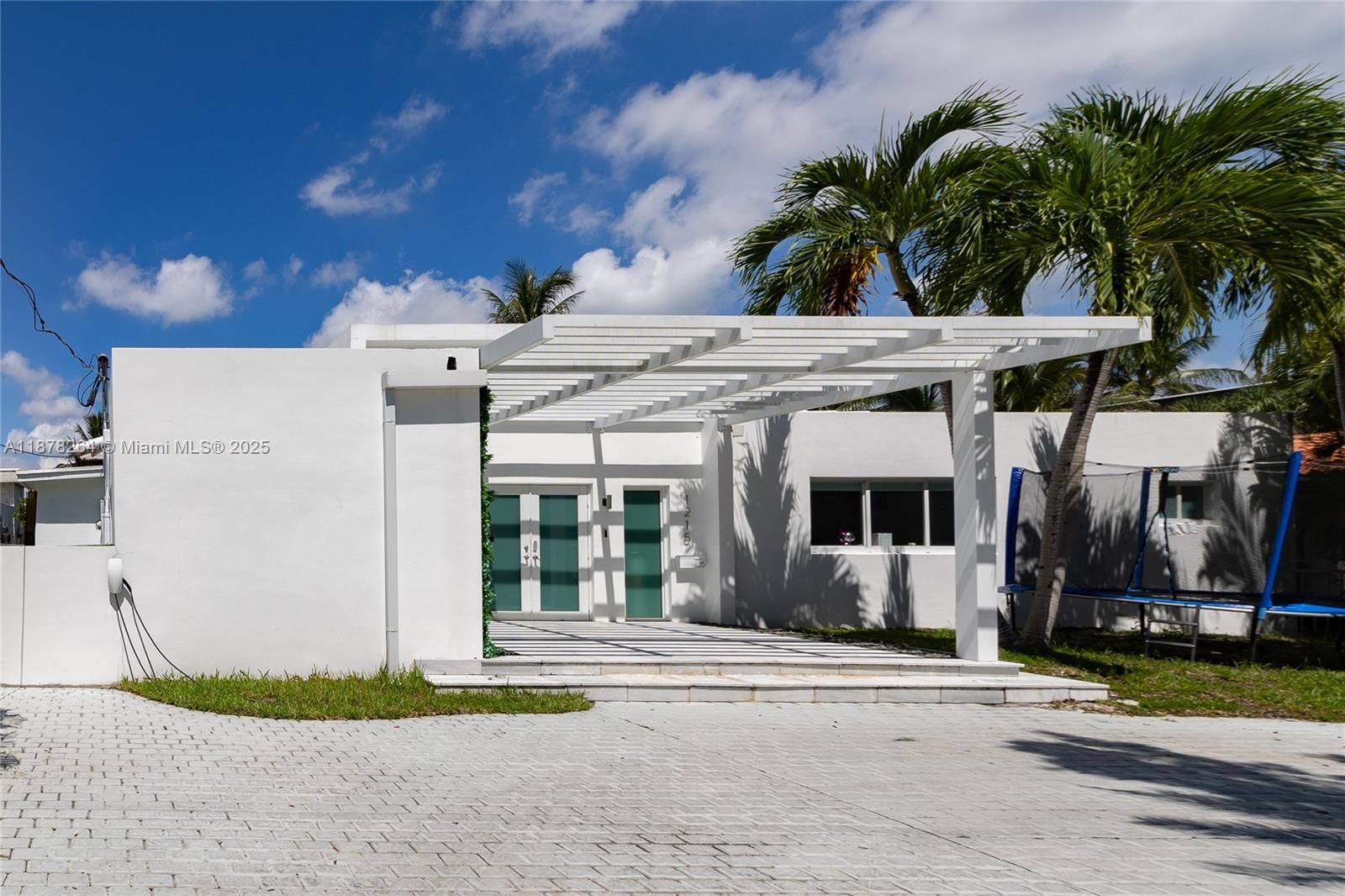 A white modern house features a pergola-covered entrance and a paved driveway — 1215 N Biscayne Point Rd, Miami Beach FL 33141, MIAMI BEACH, FL