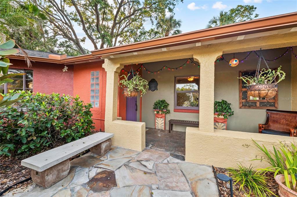A stone-paved patio leads to a covered porch with a bench and hanging plants — 941 VIRGINIA DRIVE, SARASOTA, FL