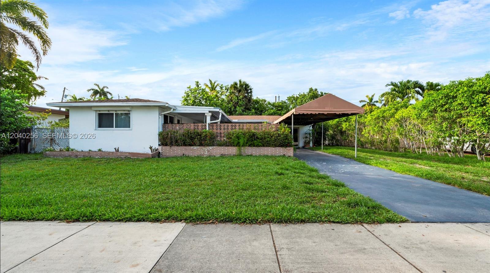 A single-story house with a white exterior, a brown carport, and a brick planter wall — 3145 Hollywood Blvd, Hollywood FL 33021, HOLLYWOOD, FL