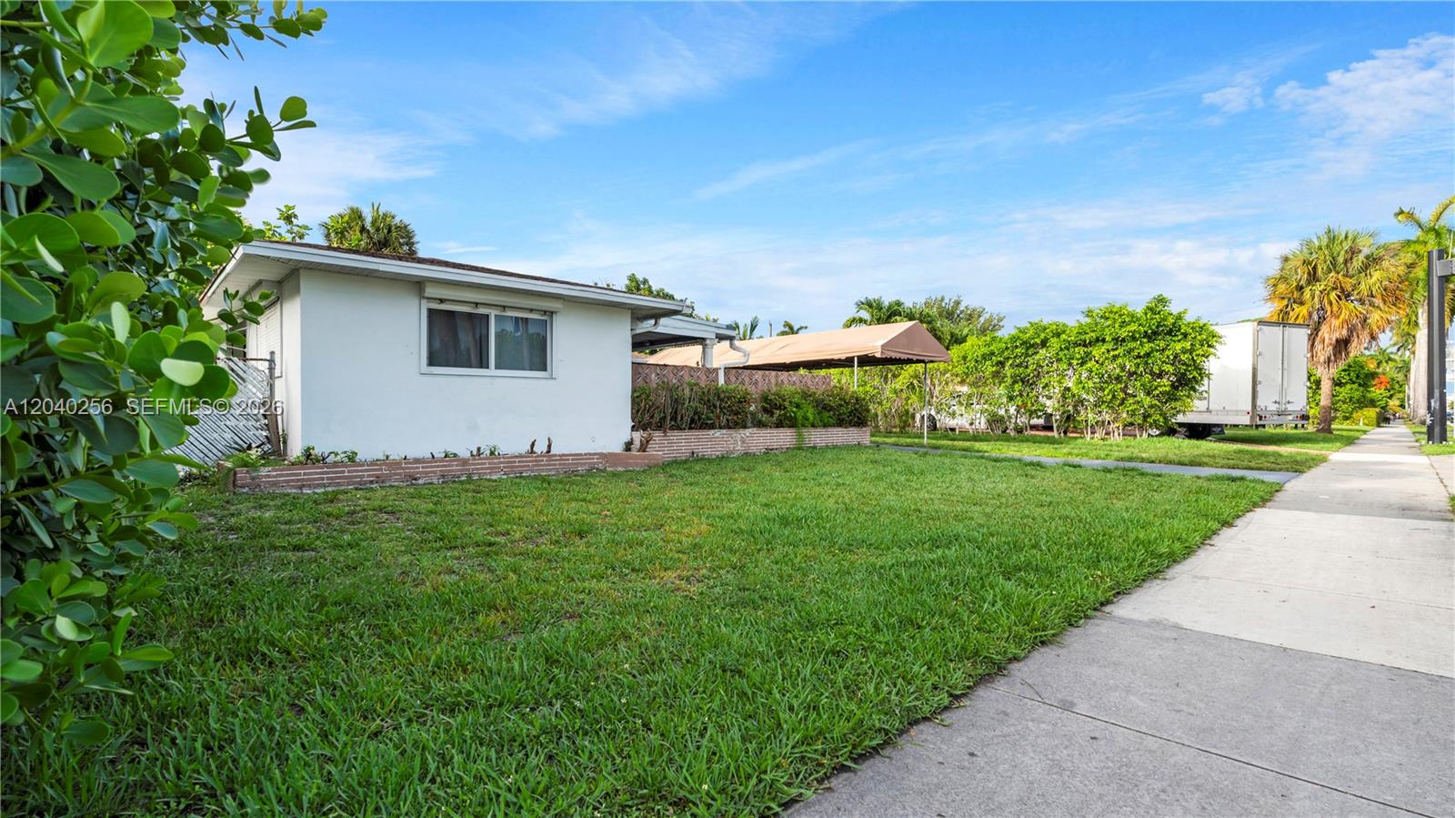 A single-story white house with a lawn and a carport sits beside a sidewalk — 3145 Hollywood Blvd, Hollywood FL 33021, HOLLYWOOD, FL