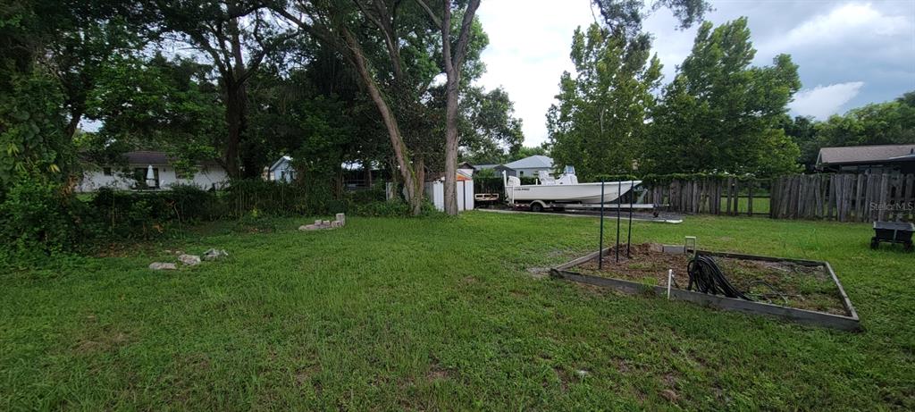 A grassy backyard features a boat on a trailer, a shed, and a raised garden bed — 226 AGUA VISTA STREET, DEBARY, FL