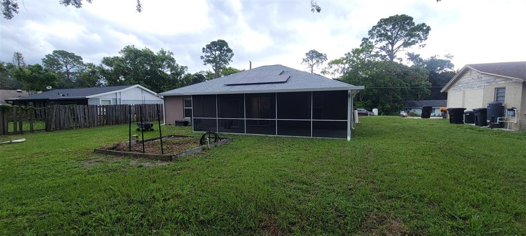 The backyard features a house with a screened-in porch and solar panels on the roof — 226 AGUA VISTA STREET, DEBARY, FL